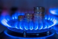 Gas stove lit, with stacks of coins above it. Increase in gas costs and tariffs. — Photo